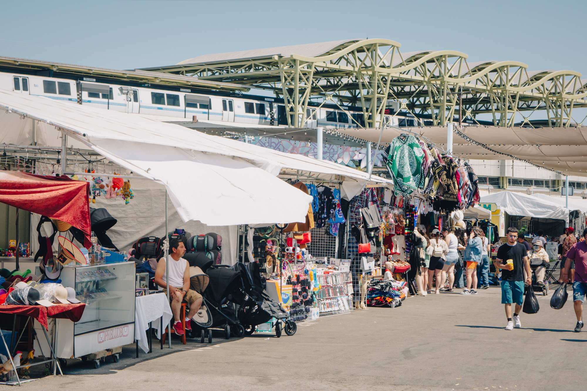 Vendors stalls with people walking by are seen in front of a large public transit station.